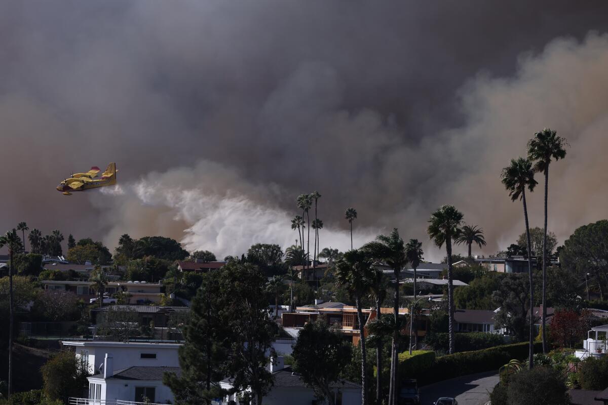 A firefighting helicopter makes a water drop on the Palisades fire.