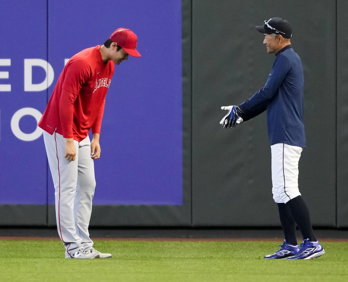 Angels' Shohei Ohtani, left, bows to former Seattle Mariners player Ichiro Suzuki before a baseball game 