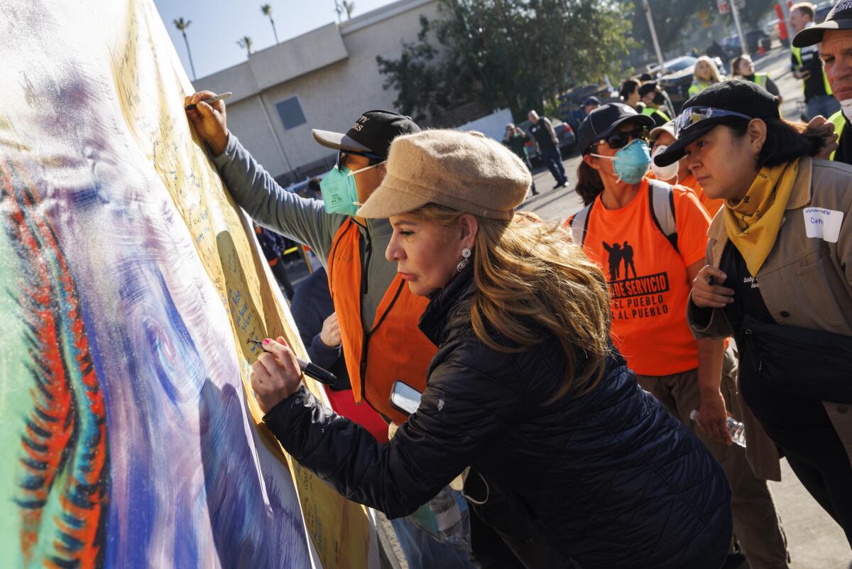 Delma Moreno signs a mural outside the Pasadena Community Job Center