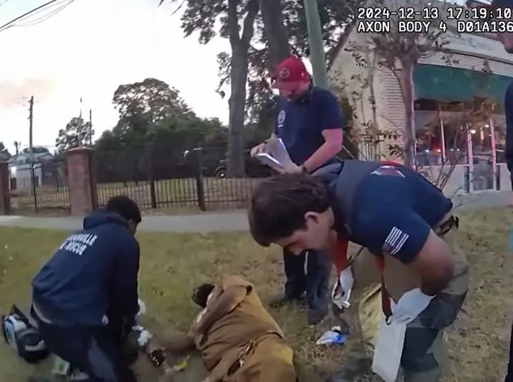 Police officers attending to a man on the ground after a firearm discharged.