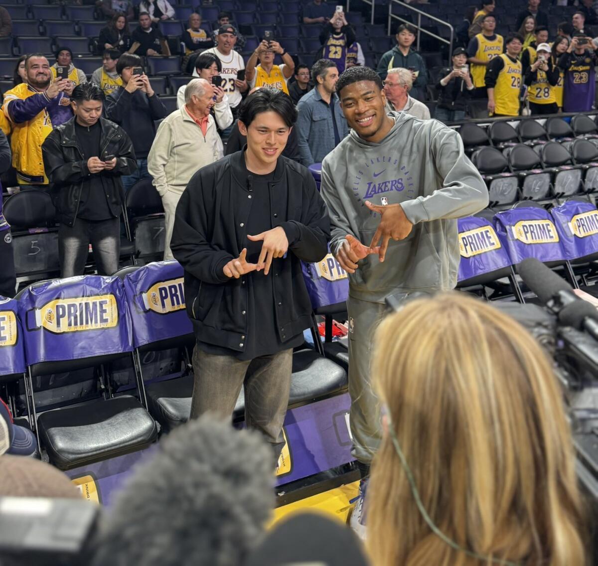 Dodgers pitcher Roki Sasaki, left, and Lakers forward Rui Hachimura make the "L.A. fingers" sign for photographers.