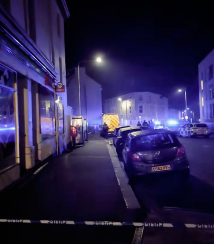 Police cars and emergency vehicles at night at a crime scene.