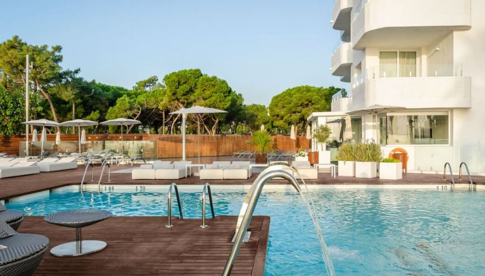 Hotel pool with surrounding lounge chairs and umbrellas.