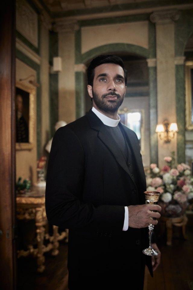 Reverend Alphy Kotteram from Grantchester holding a glass.