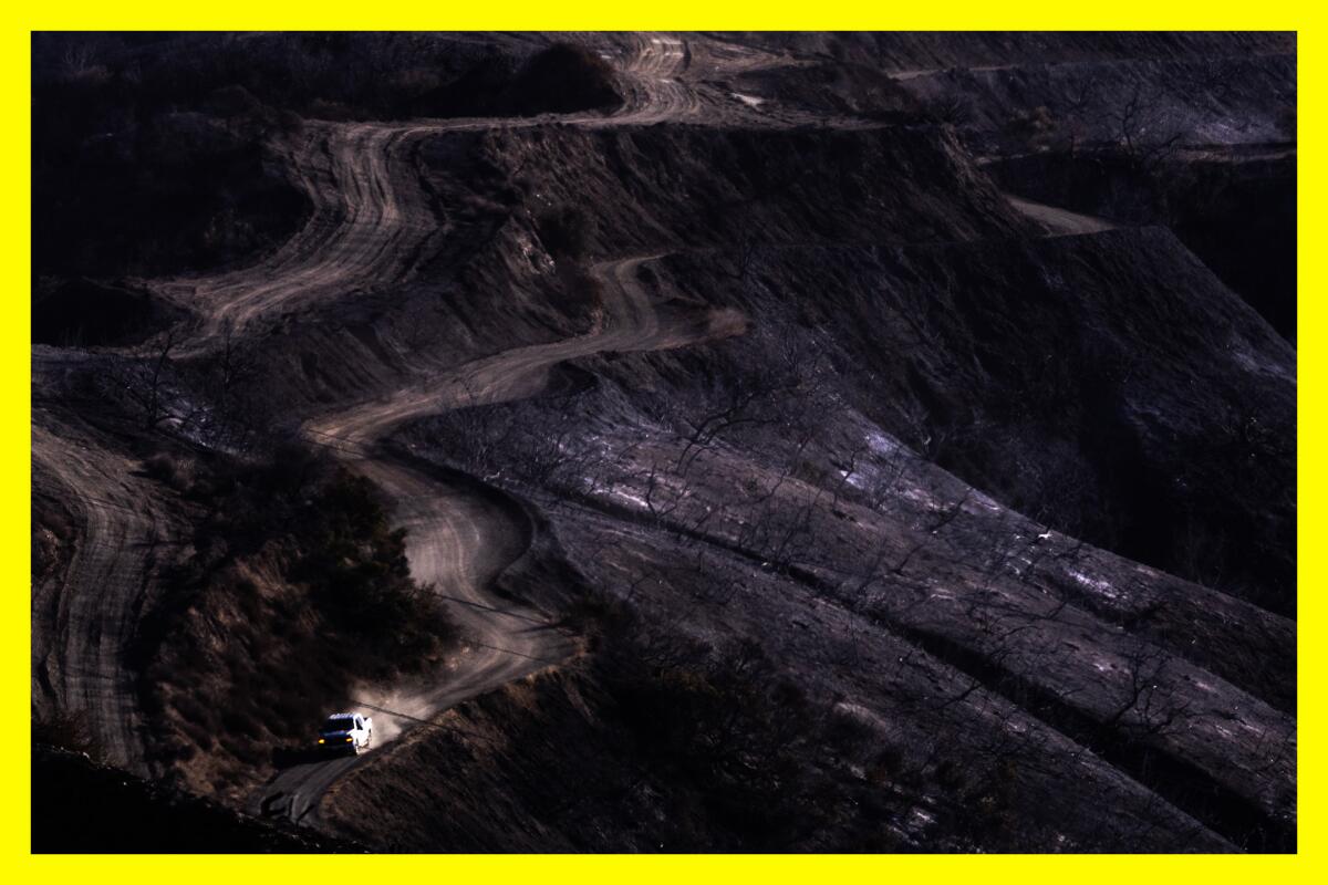 A lone vehicle passes through deeply scorched hills.