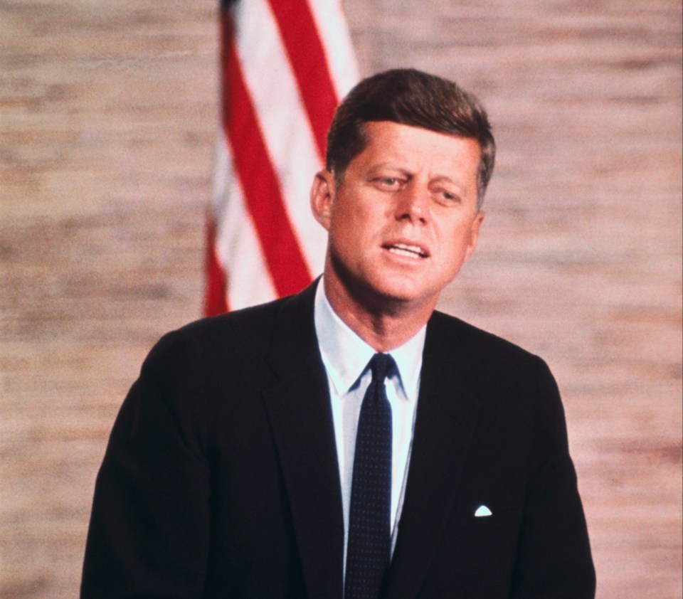 President John F. Kennedy speaking at a podium.