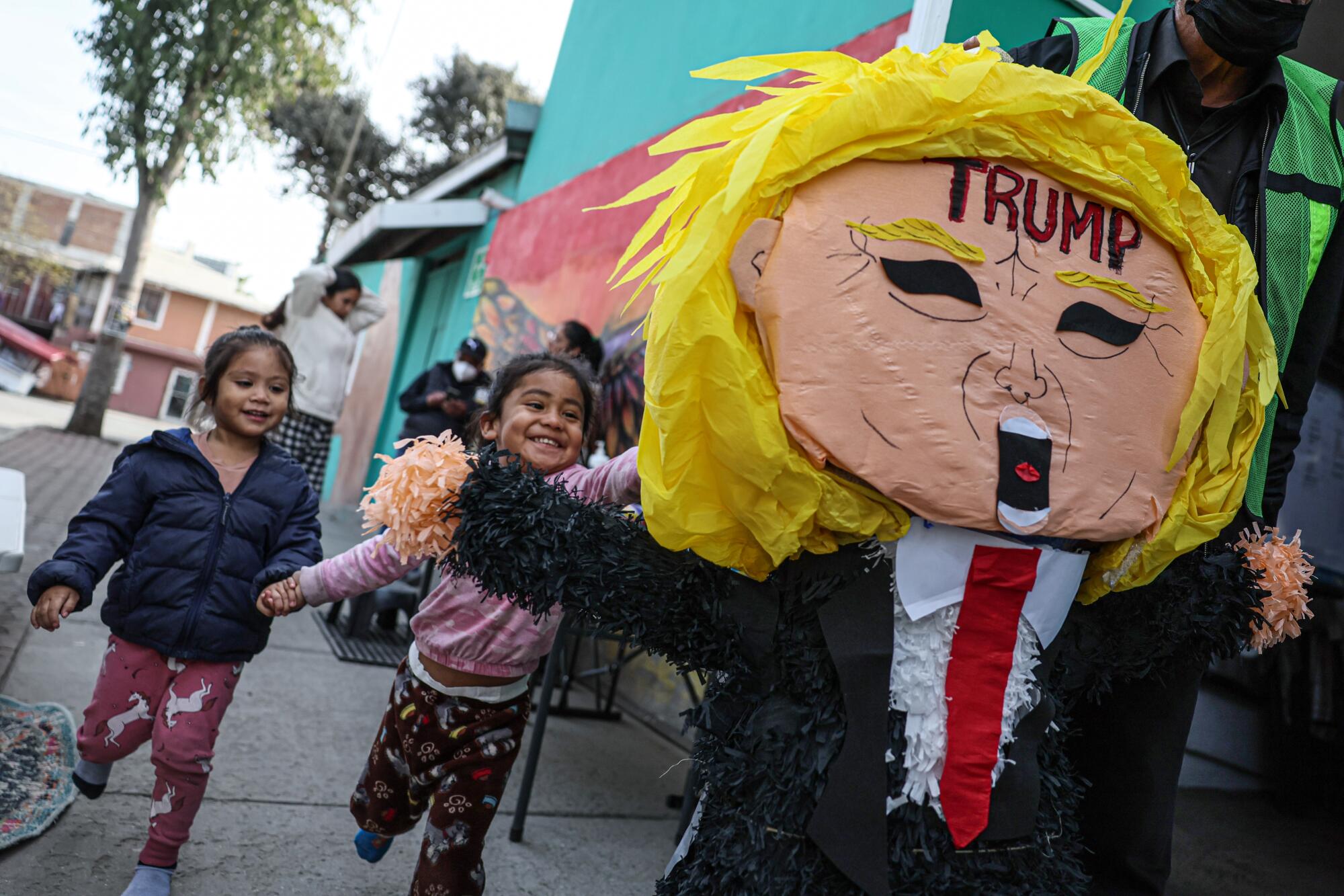 Children laugh as they chase a piñata that looks like President Trump. 