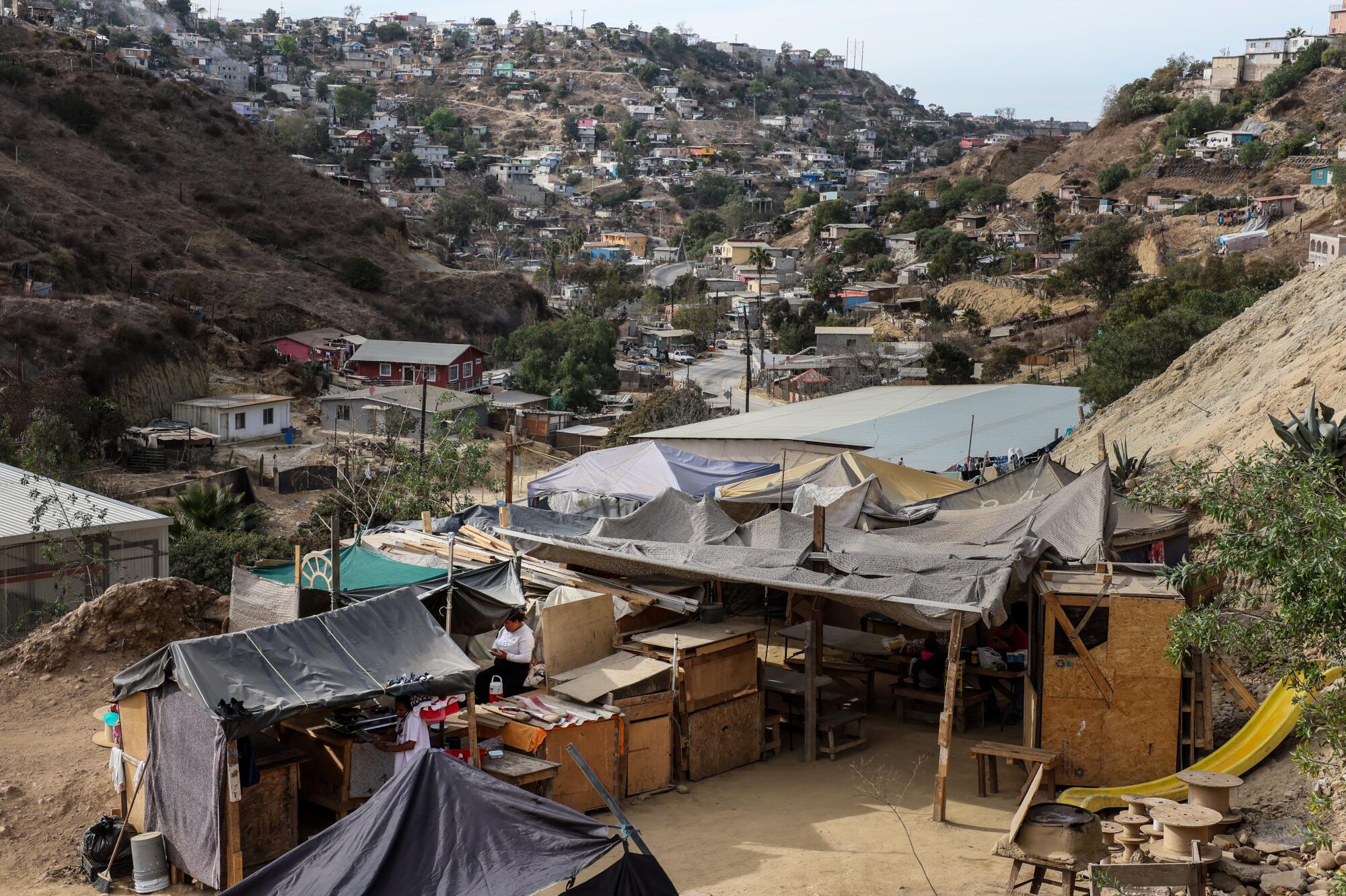 Asylum seekers cook a meal amid tarps and tents at a shelter. 