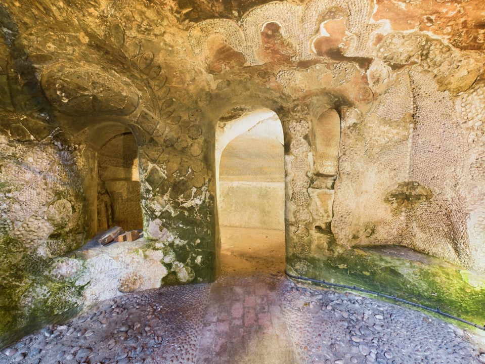 Interior of a temple-style cave with stone walls and a pebble floor.