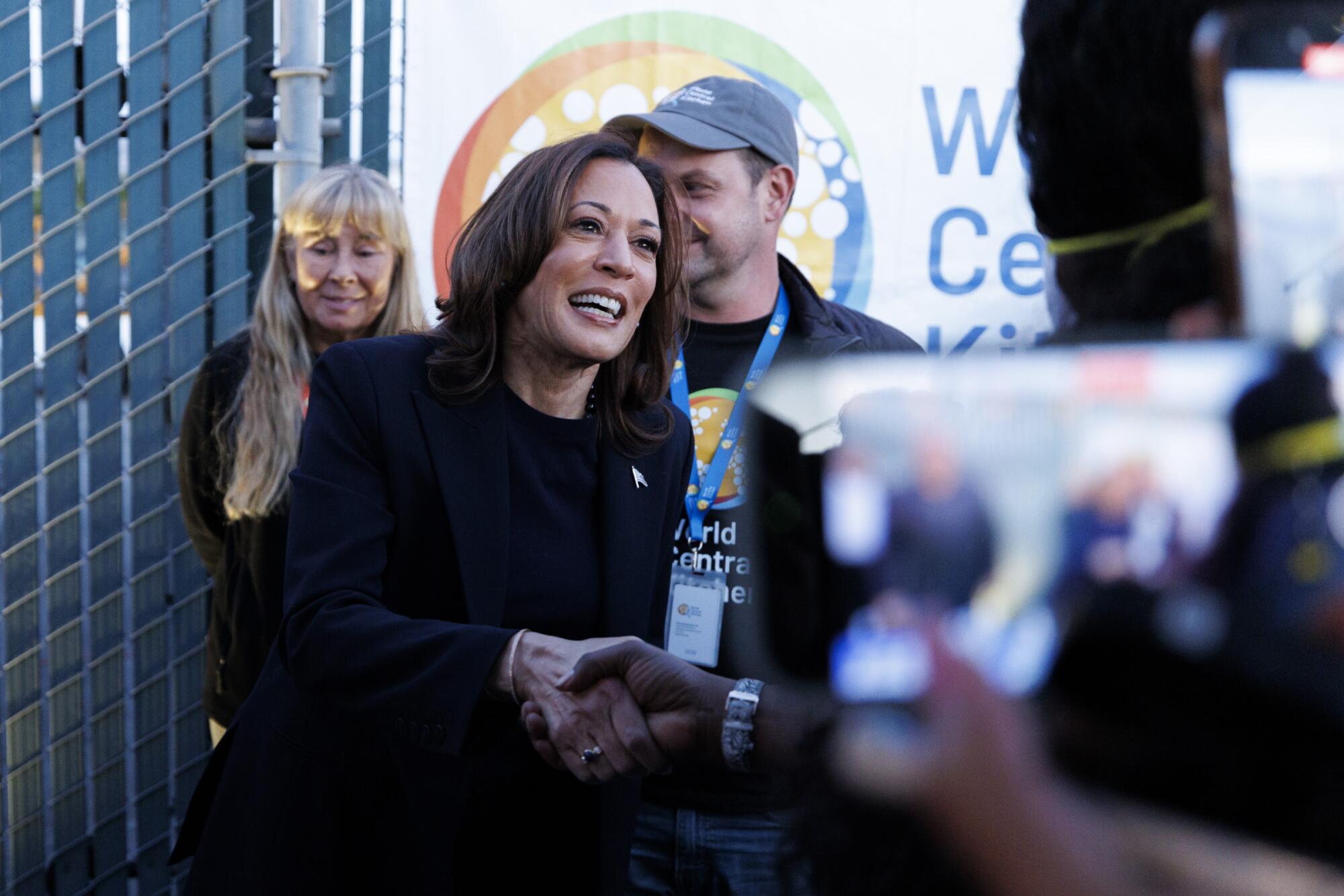 A woman smiles while shaking someone's hand.