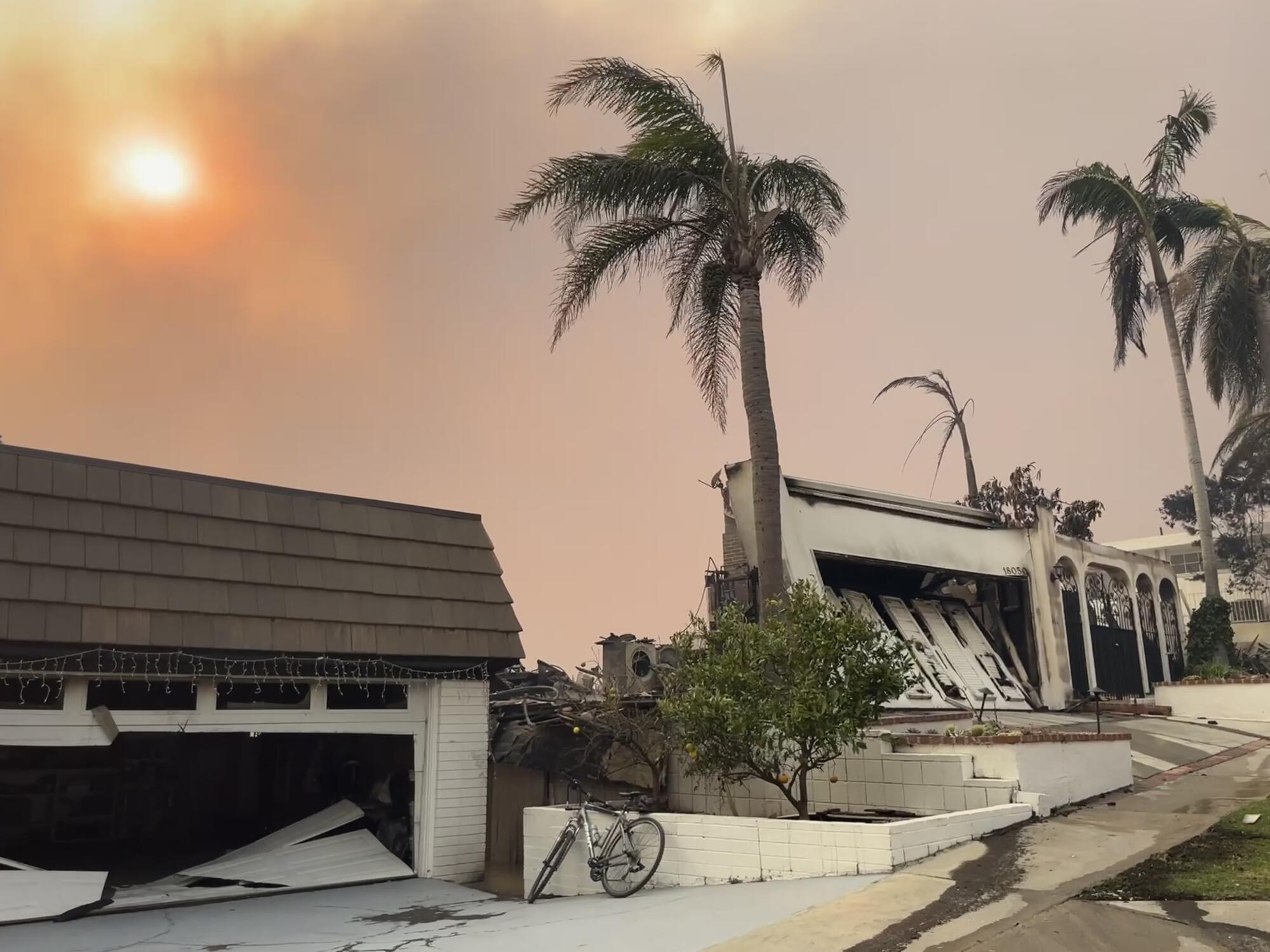 Fire-damaged homes beneath a smoke-shrouded sky