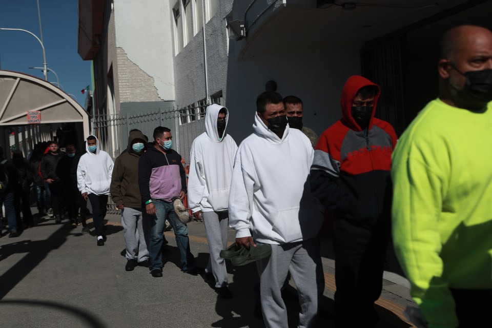 A group of men wearing masks walk along a street in Ciudad Juarez, Mexico, after being deported from the United States.