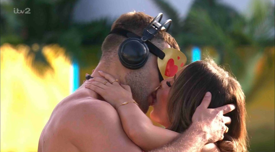 Couple kissing while wearing a heart-shaped blindfold.