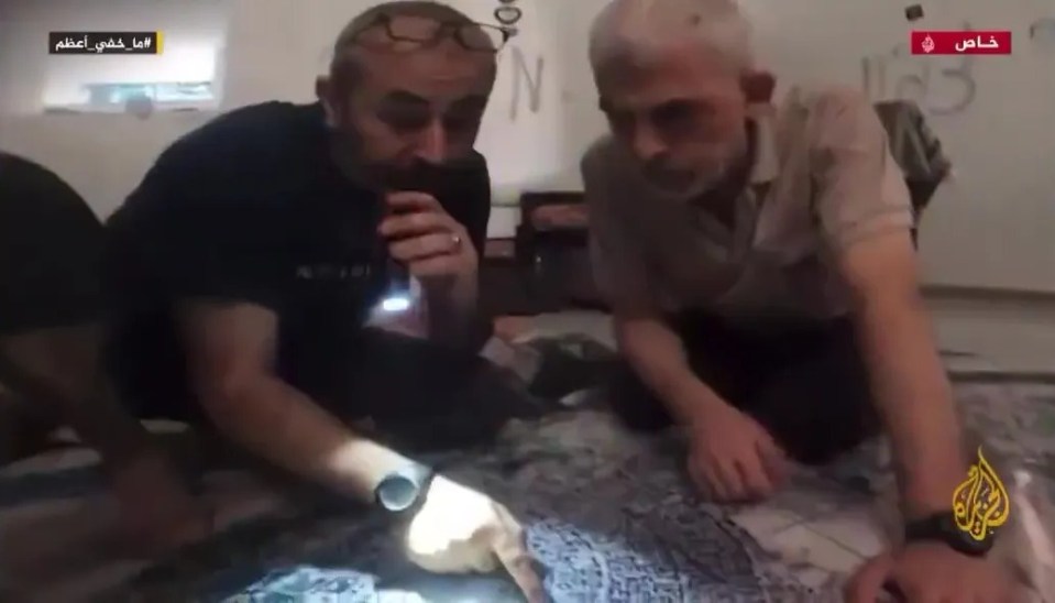 Footage of two men examining something on a floor.