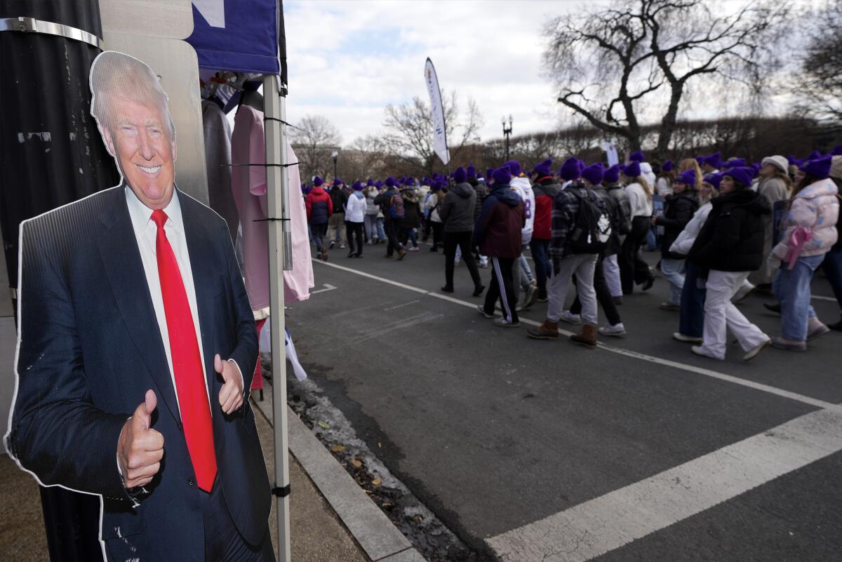 People participating in an anti-abortion march walk past a cardboard cutout of President Trump giving a thumbs up. 