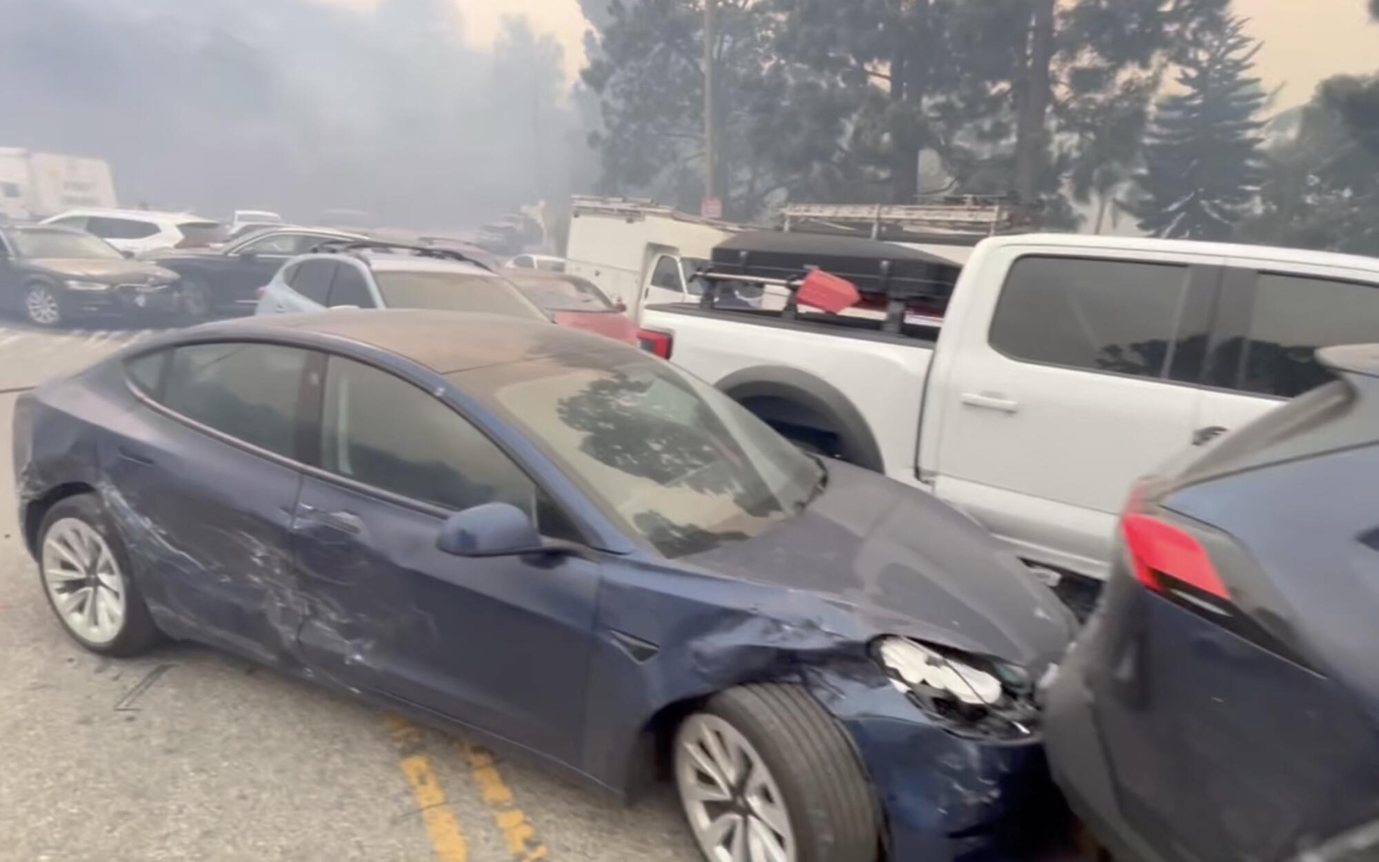 Abandoned cars clog a smoky roadway.