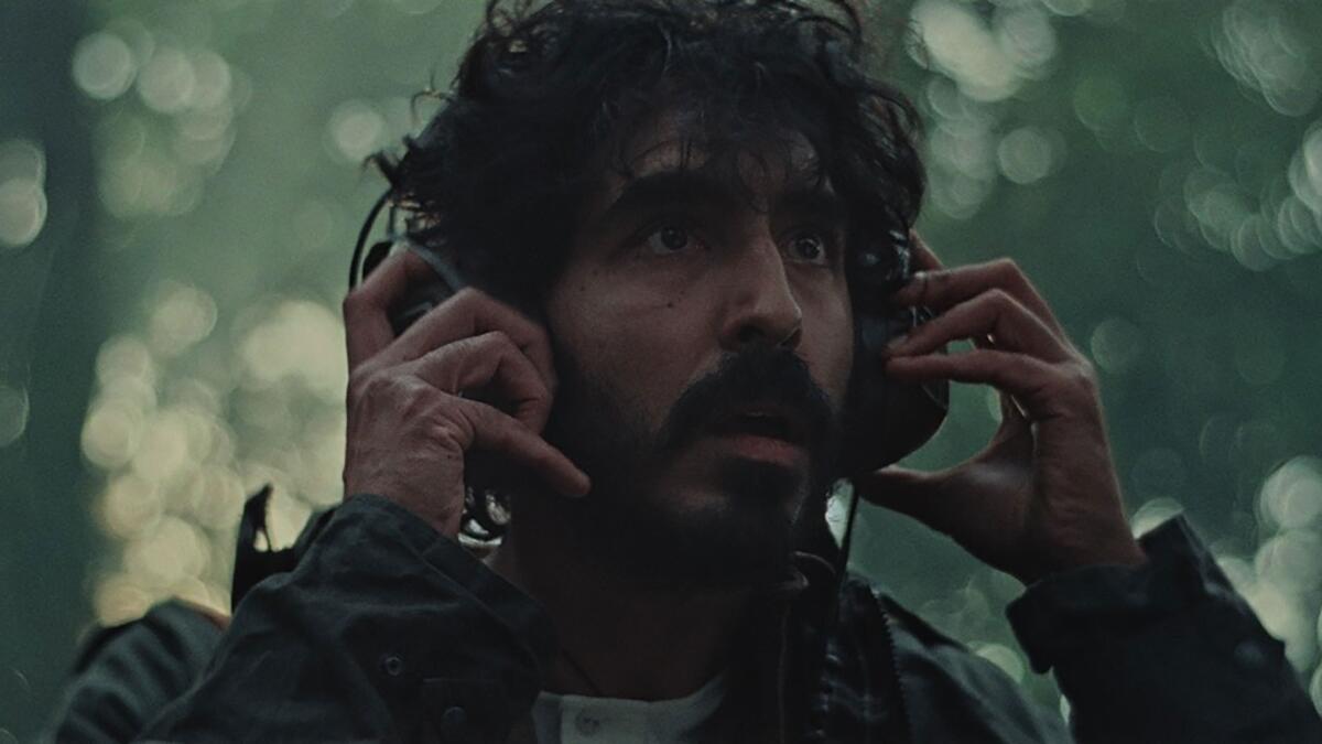 A man listens on headphones in the woods.