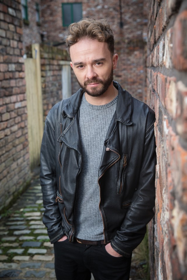 Jack P. Shepherd, actor in Coronation Street, leaning against a brick wall.