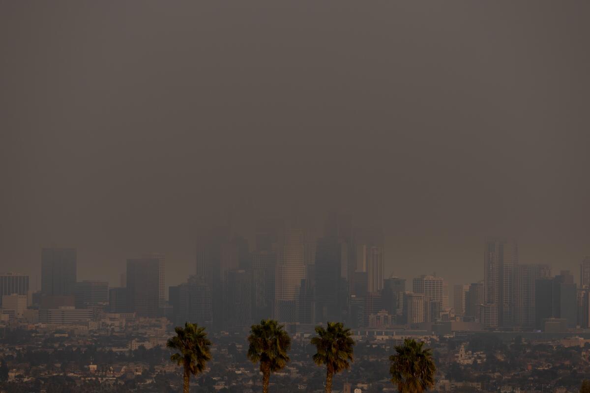 Dense gray wildfire smoke mostly obscures a view of downtown Los Angeles. 