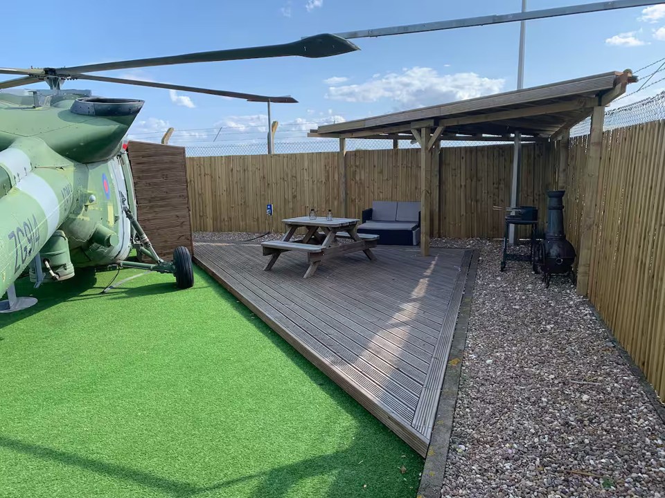 Decking area with picnic table and seating next to a helicopter.