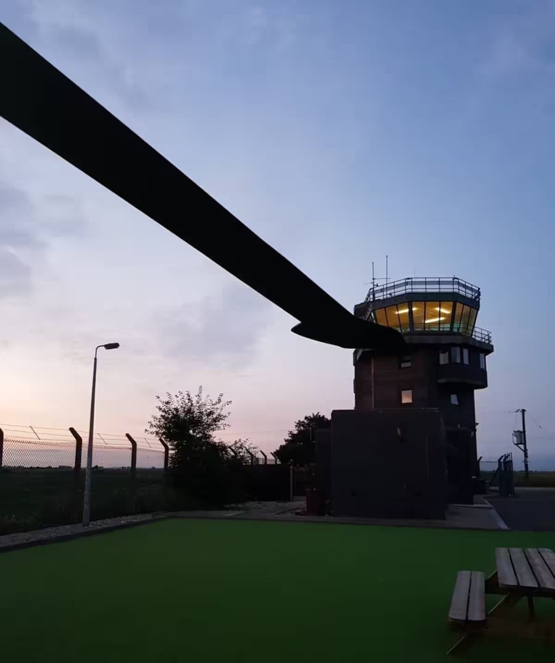 Helicopter blade and air traffic control tower at dusk.