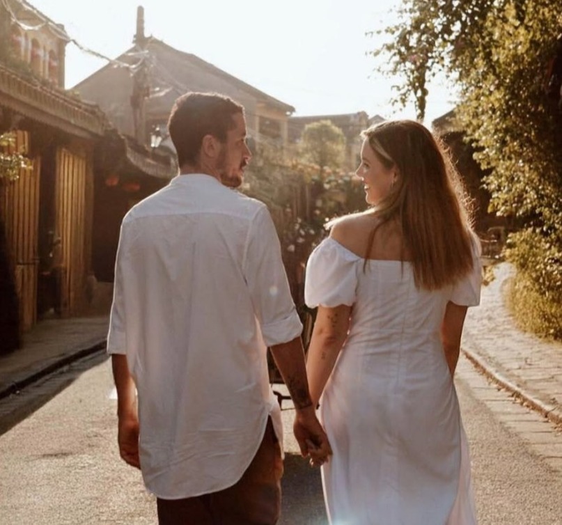 Couple holding hands and walking down a street.