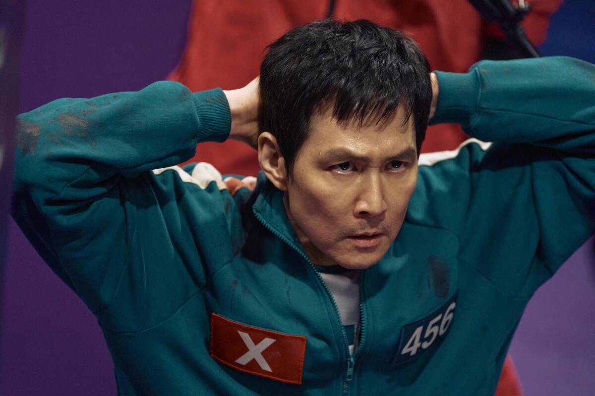 a man in a green tracksuit with his hands behind his head