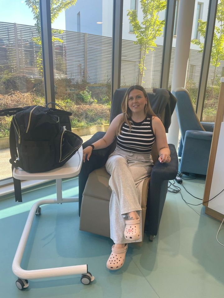 Woman sits in a chair in a hospital waiting room.