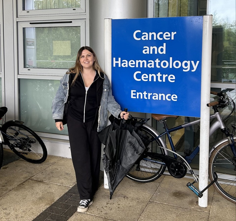 Woman standing outside a Cancer and Haematology Centre entrance.