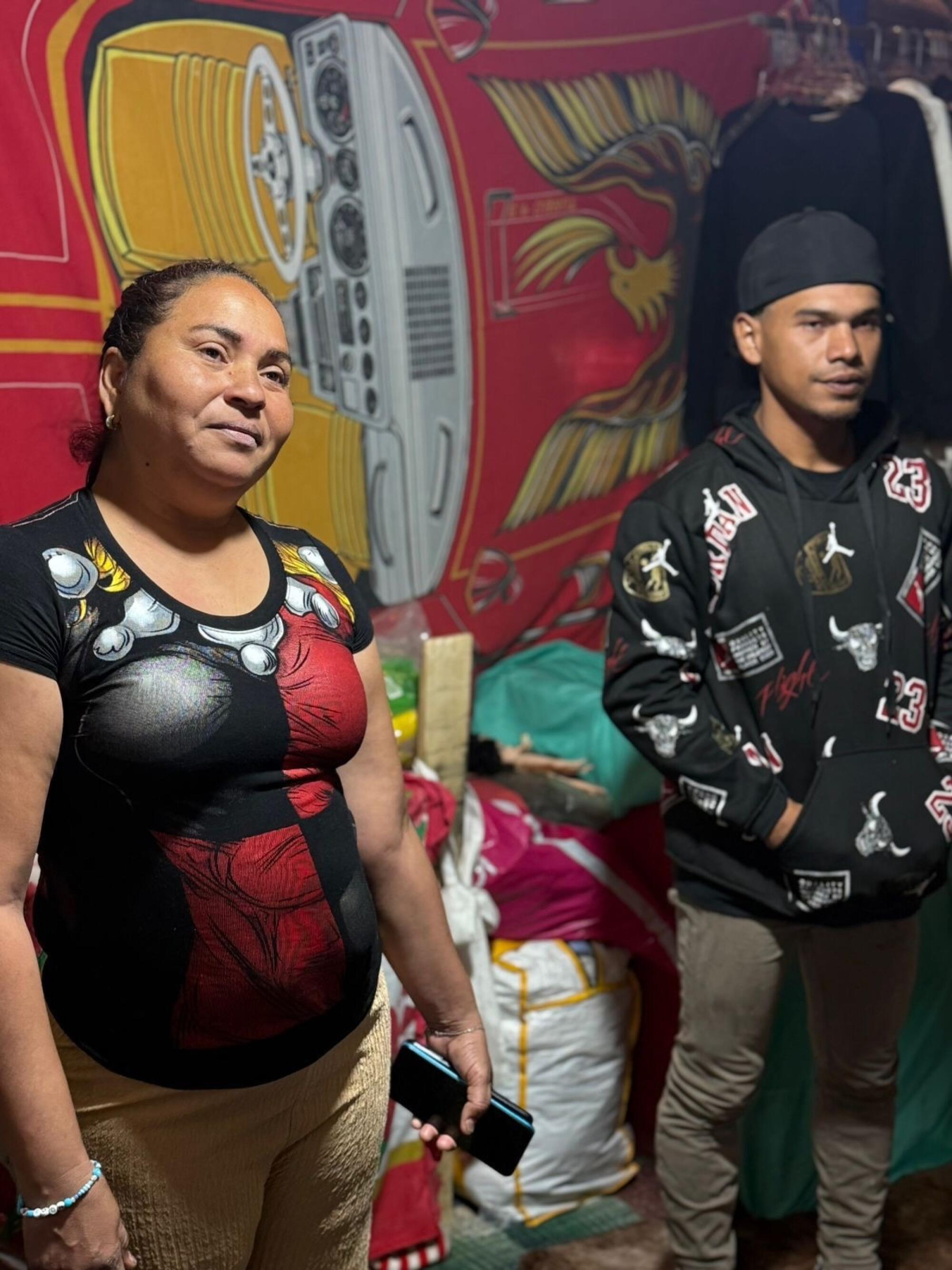 A man and woman stand in front of a colorful mural.