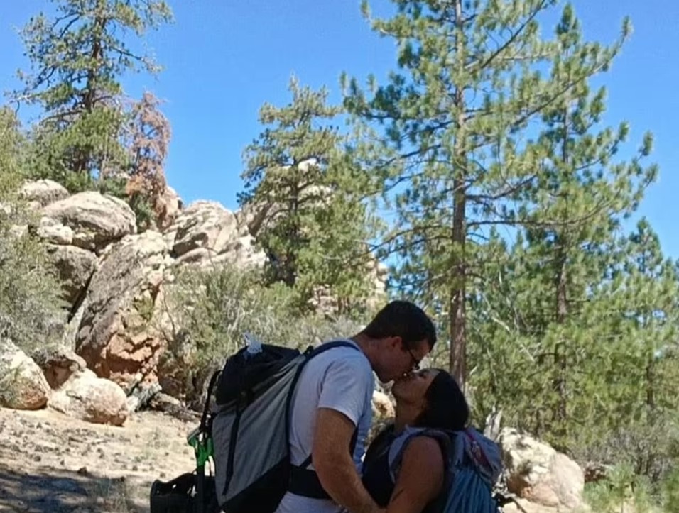 Couple kissing in front of rocky landscape.