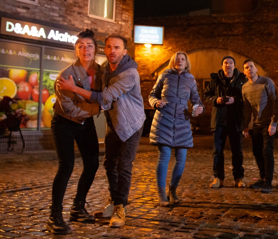 A scene from Coronation Street showing Shona Platt and David Platt reacting to an explosion.