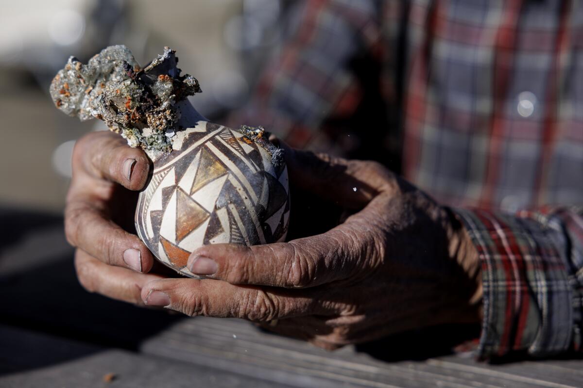 Ted Ancona holds a small piece of brown, white and gray pottery.