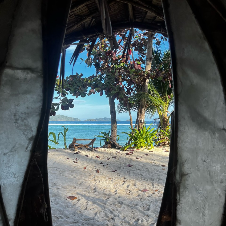 View of a tropical beach through a hut's opening.