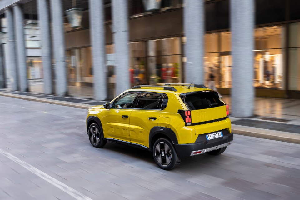 Yellow SUV driving down a city street.