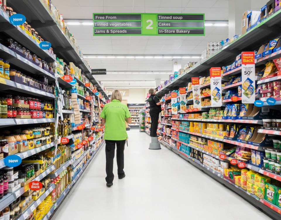 Aisles in a supermarket with staff stocking shelves.