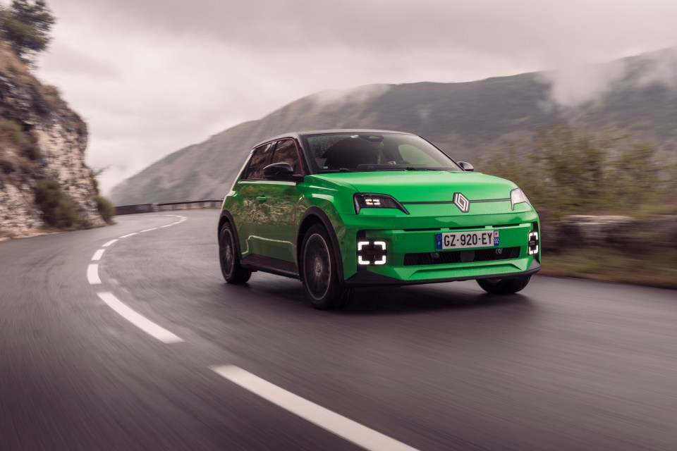 Green electric car driving on a mountain road.