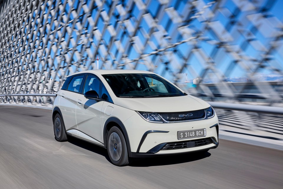 BYD Dolphin electric car driving on a bridge.