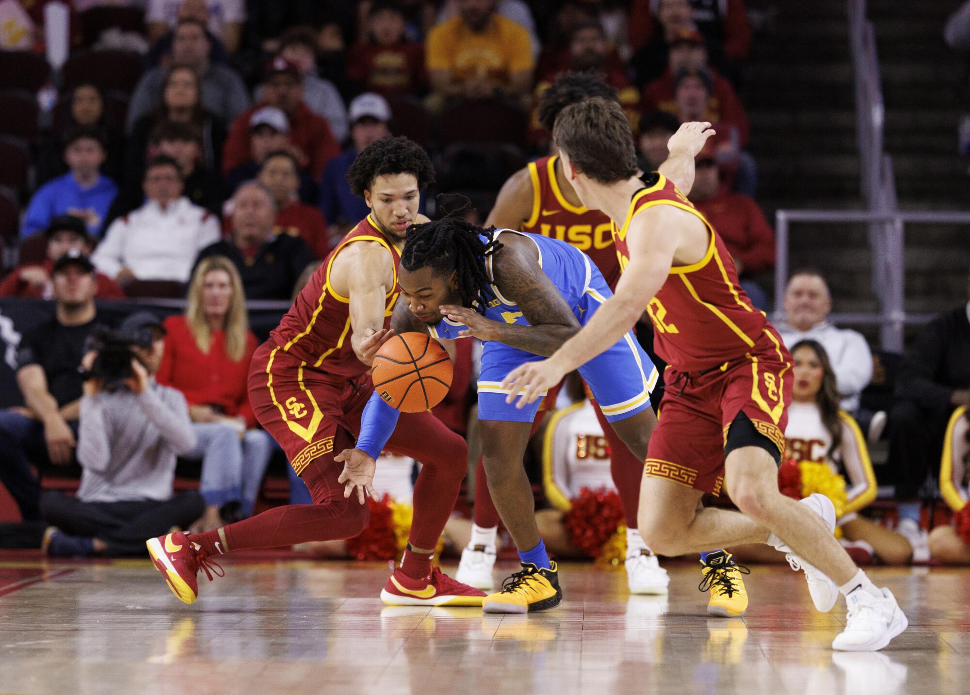 UCLA guard Sebastian Mack dribbles though pressure from USC guards Desmond Claude and Clark Slajchert 