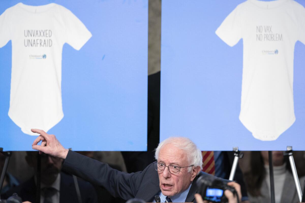 Sen. Bernie Sanders points to a display of anti-vaccination infant onesies during Robert Kennedy's confirmation hearing.