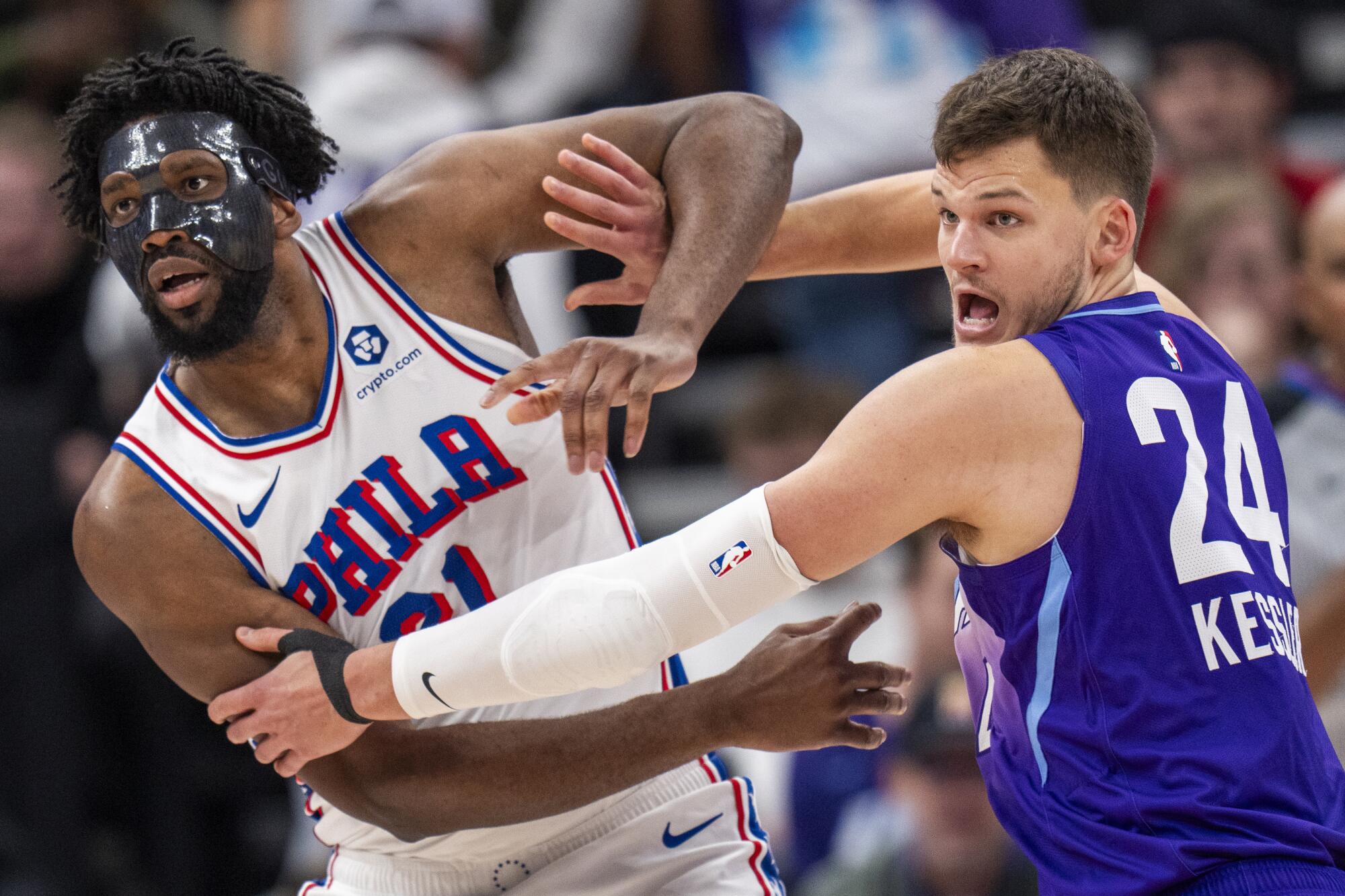 Sixers center Joel Embiid battles Utah center Walker Kessler for position during a basketball game.