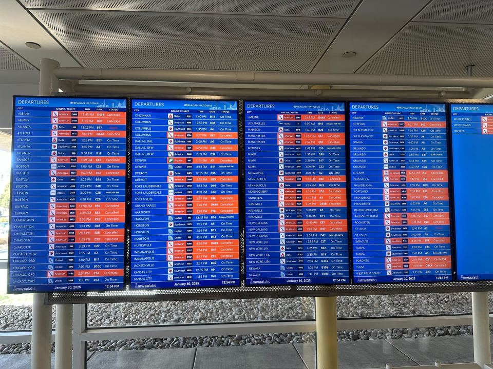 Departure board at Ronald Reagan airport showing flight information.