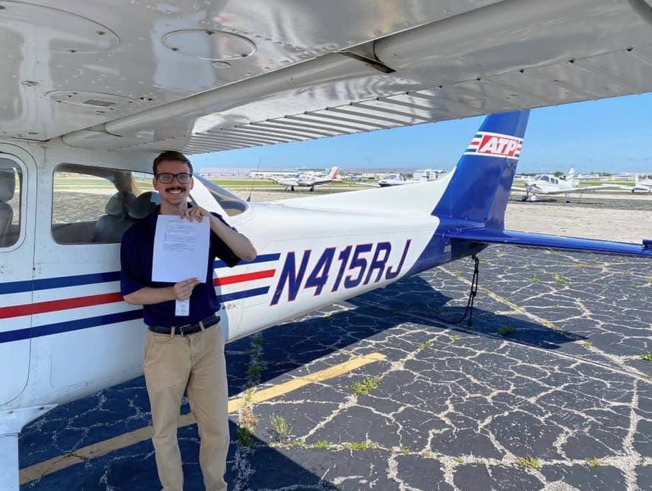 Man standing next to small airplane holding a document.