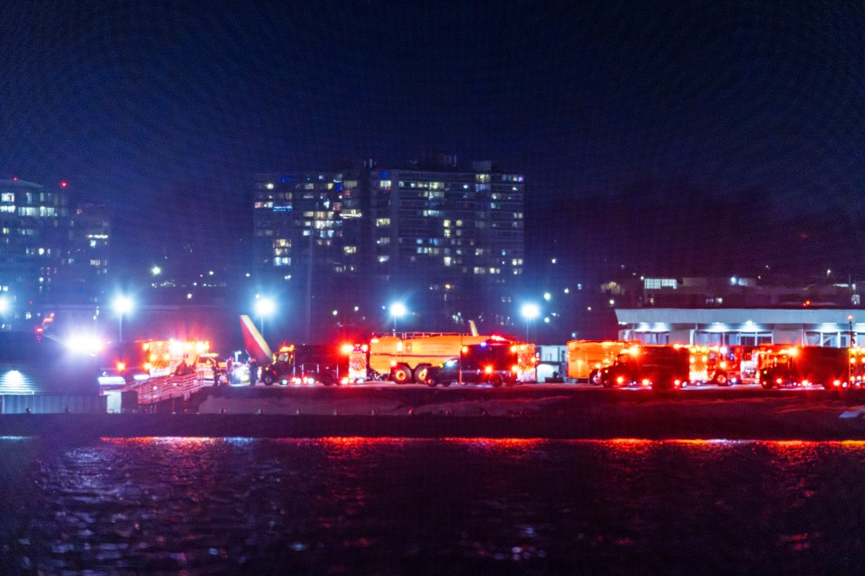 Emergency vehicles at night near an airplane.