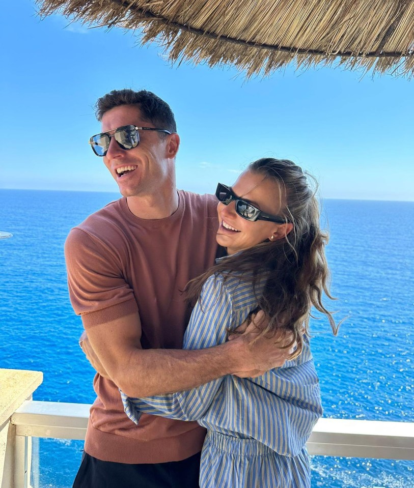 Robert and Anna Lewandowska embracing on a balcony overlooking the ocean.