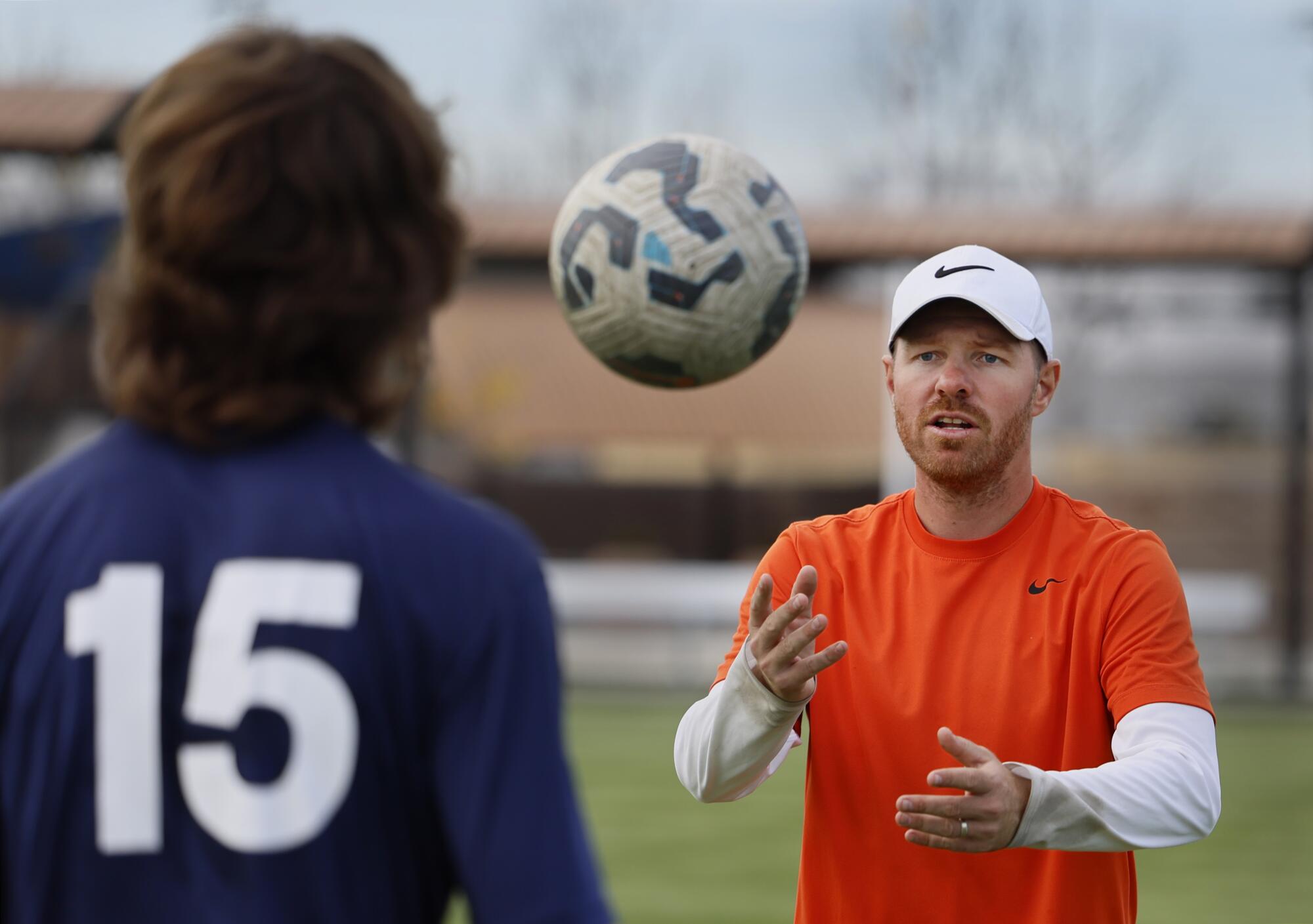 Coach/trainer Michael Holzer throws a soccer ball to 17-year-old player Tristan Eggerling