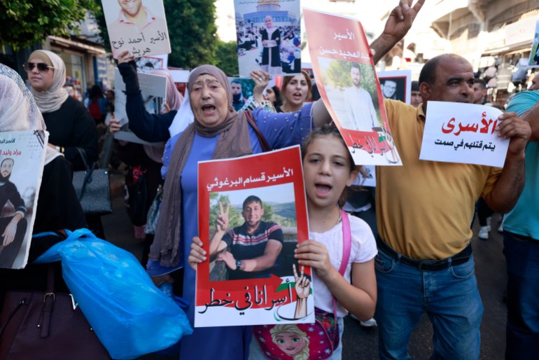 people hold photographs at a protest in a street