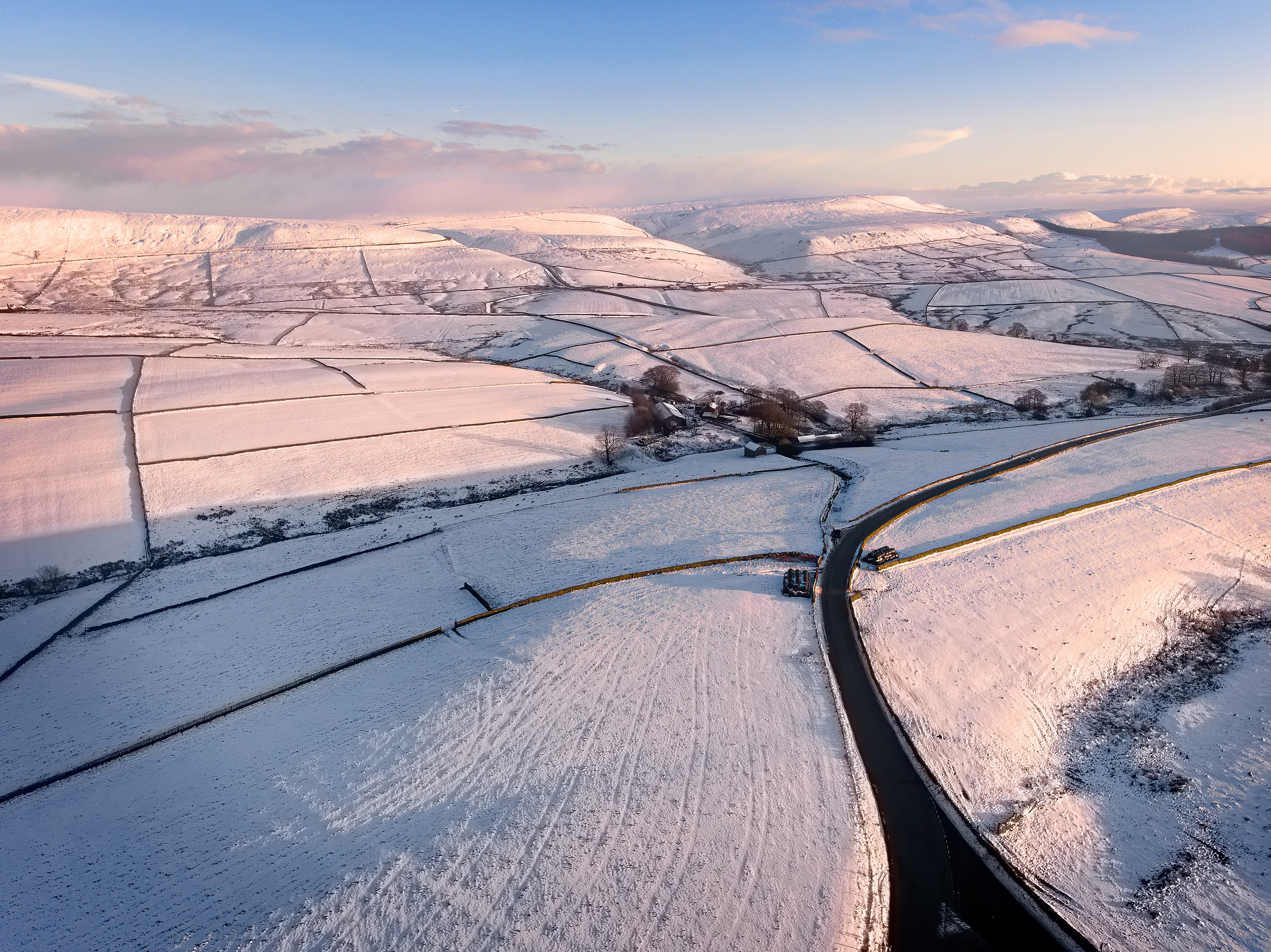 Aerial view of a snow-covered road winding through the Peak District.