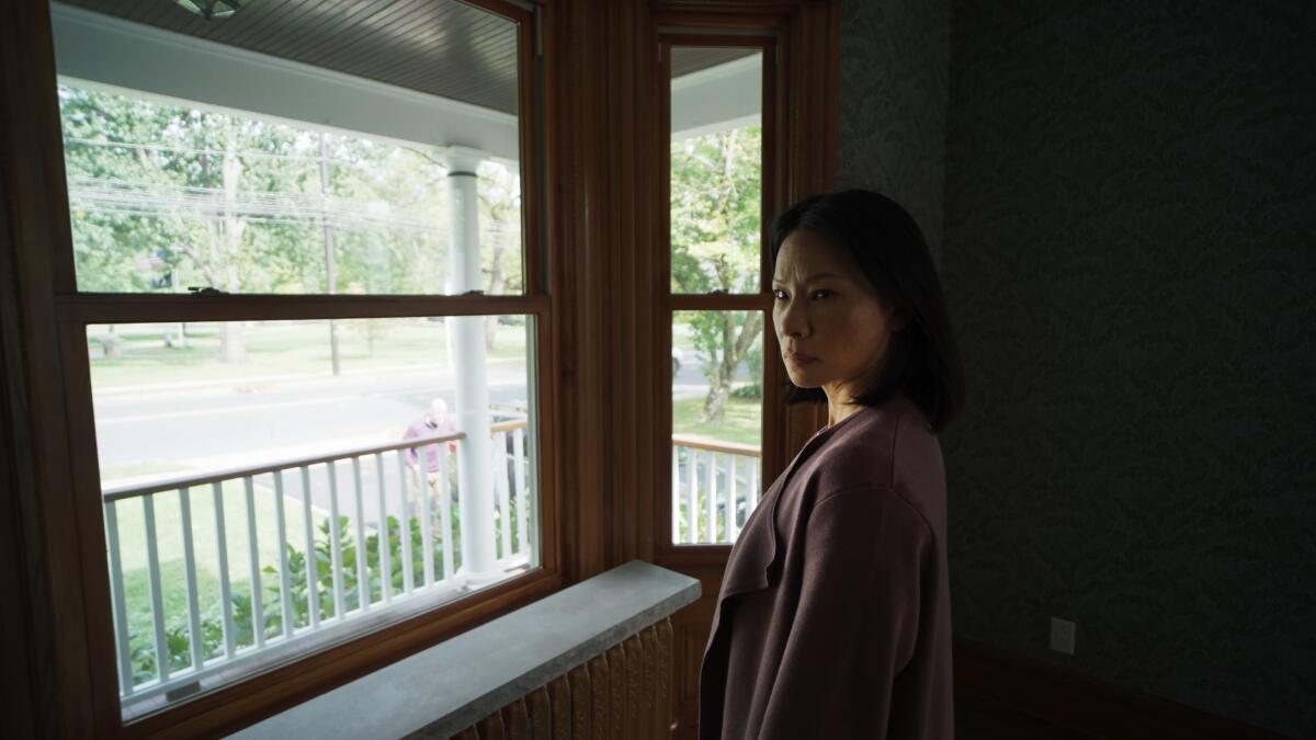 A woman at a window senses a presence next to her.