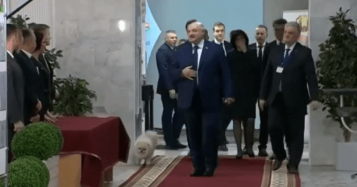 Lukashenko walking with a small dog and his entourage.